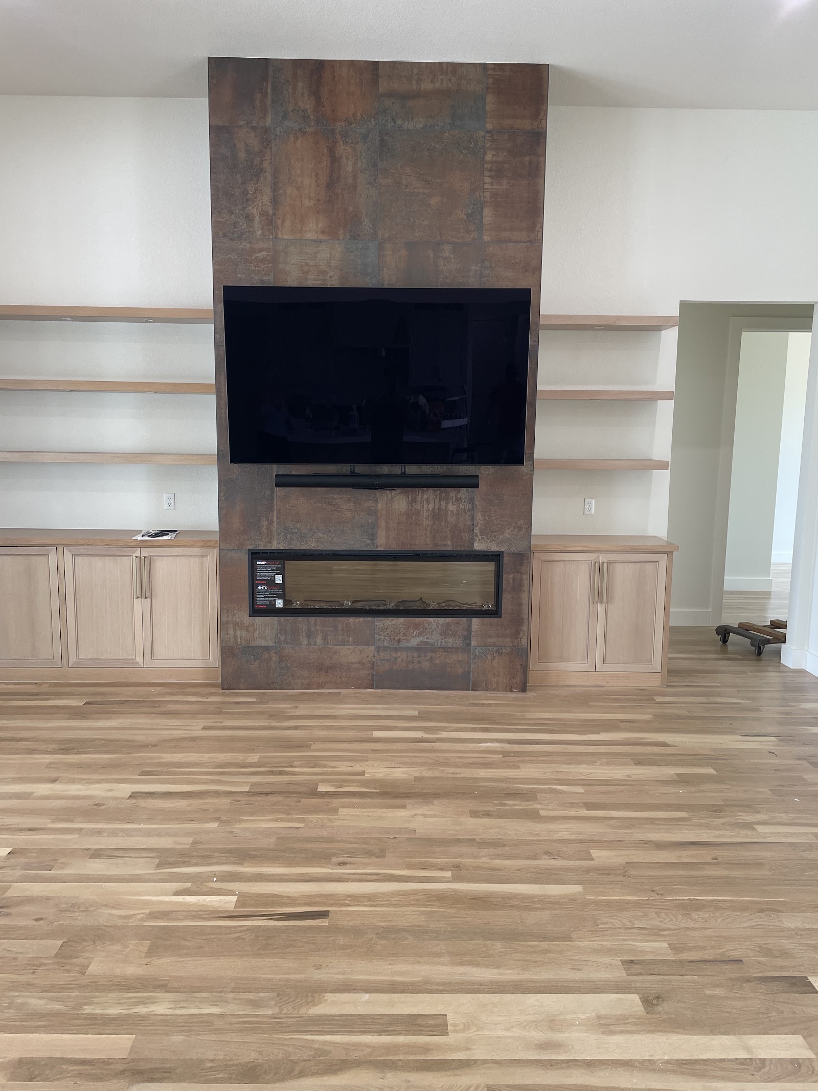 Custom media wall with floating shelves, cabinets, and tiled fireplace surround by LKP Woodworks